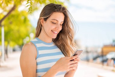 Dışarıdaki güzel bayan cep telefonuyla mesaj ya da e-posta yolluyor.