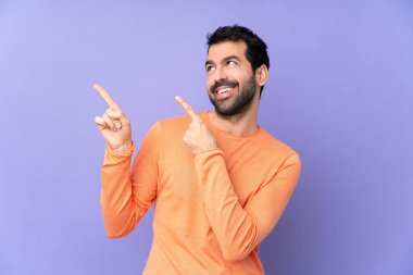 İzole edilmiş mor arka planda beyaz, yakışıklı bir adam işaret parmağıyla işaret etmek harika bir fikir.