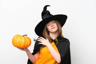 Cadı kostümü giymiş güzel bir kadın beyaz arka planda izole edilmiş bir balkabağı tutuyordu. Çabaladığı için omuz ağrısı çekiyordu.