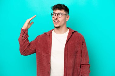 Kafkasyalı yakışıklı genç adam mavi arka planda izole edilmiş, yorgun ve hasta bir ifadeyle.