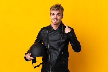 Motosiklet kasklı bir adam sarı arka planda izole edilmiş bir şekilde baş parmak hareketi yapıyor.