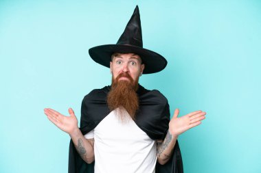 Cadılar Bayramı 'ndaki genç büyücü mavi arka planda yalnızken ellerini kaldırırken şüpheye düşüyor.