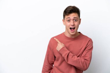 Beyaz arka planda izole edilmiş yakışıklı Brezilyalı adam şaşırmış ve işaret ediyor.