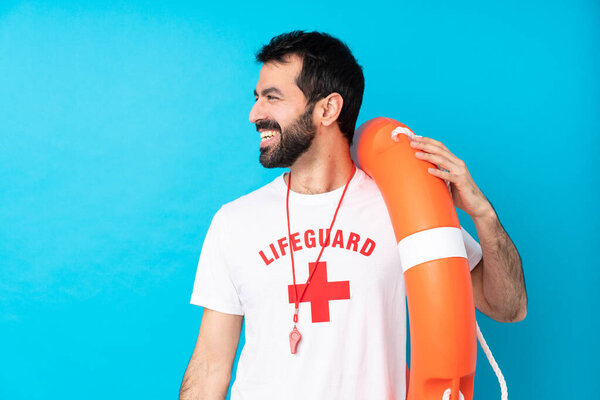 Lifeguard man over isolated blue background looking side