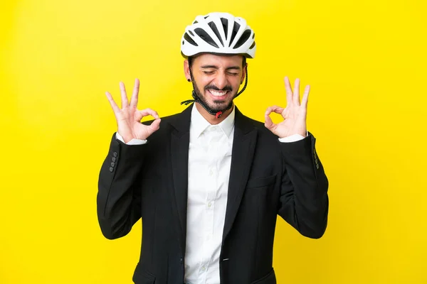 Business caucasian man with a bike helmet isolated on yellow background in zen pose