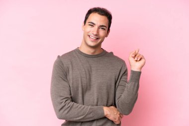 Pembe arka planda izole edilmiş genç beyaz adam mutlu ve yukarıya bakıyor.