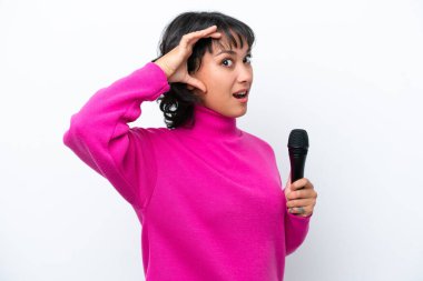 Genç Arjantinli şarkıcı kadın, beyaz arka planda izole edilmiş. Yan tarafa bakarken sürpriz jest yapıyor.