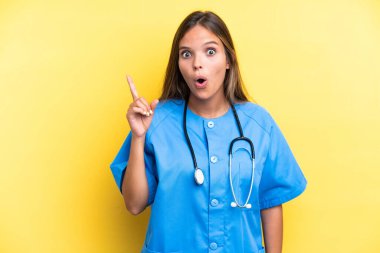 Sarı arka planda izole edilmiş beyaz bir kadın hemşire. Çözümü bulmak için parmağını kaldırıyor.