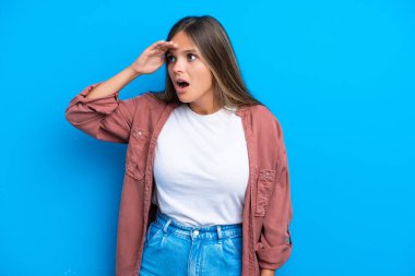 Mavi arka planda mahsur kalmış beyaz bir kadın. Sürpriz bir ifadeyle yan tarafa bakarken.