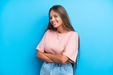 Mavi arka planda izole edilmiş, kolları çapraz ve ileriye bakan beyaz bir kadın.