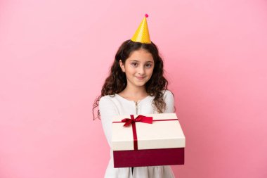 Küçük beyaz kız elinde pembe arka planda izole edilmiş mutlu bir ifadeyle bir hediye tutuyor.