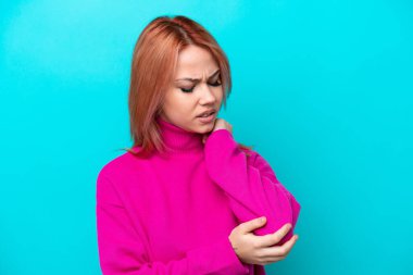 Genç Rus kadın mavi arka planda izole edilmiş, dirseğinde ağrı var.