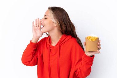Beyaz arka planda izole edilmiş patates kızartması tutan genç bir Rus kızı ağzı açık bağırıyor.