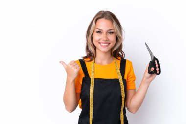 Beyaz arka planda izole edilmiş genç Rus terzi kız bir ürün sunmak için kenarı işaret ediyor