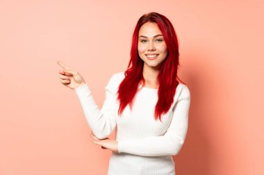 Genç kızıl saçlı kız pembe arka planda izole edilmiş.