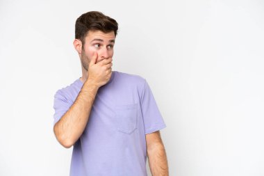 Beyaz arka planda izole edilmiş genç beyaz adam yan tarafa bakarken sürpriz jest yapıyor.