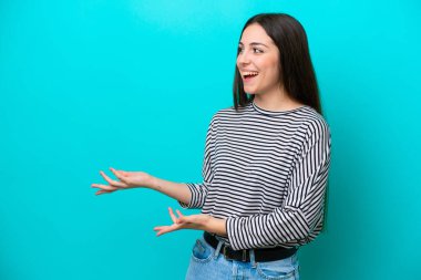 Mavi arka planda mahsur kalmış beyaz bir kadın. Sürpriz bir ifadeyle yan tarafa bakarken.