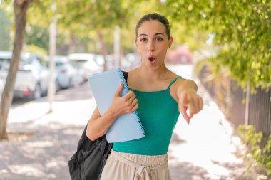 Açık alandaki genç ve güzel bayan şaşırmış ve ön tarafı işaret ediyor.