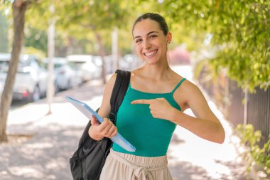 Açık havada genç ve güzel bir bayan öğrenci ve onu gösteriyor.