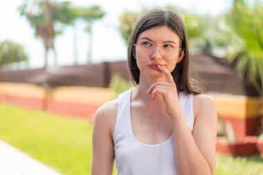 Genç ve güzel bir kadın gözlüklü ve kuşkuları var.