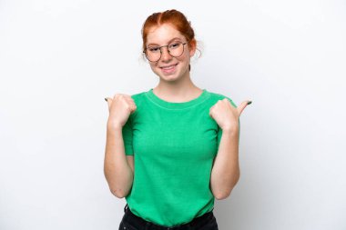 Beyaz arka planda izole edilmiş genç, kırmızı bir kadın. Baş parmakları havada ve gülümsüyor.