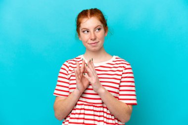 Kırmızımsı genç kadın mavi arka planda bir şeyler planlıyor.