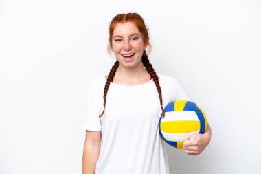 Beyaz arka planda yalıtılmış voleybol oynayan beyaz tenli, kızıl saçlı genç bir kadın.