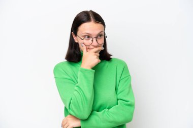 Beyaz arka planda izole edilmiş genç beyaz bir kadın. Şüpheleri var ve kafası karışmış bir yüz ifadesi var.