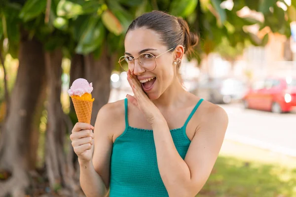 Young pretty woman with a cornet ice cream at outdoors whispering something