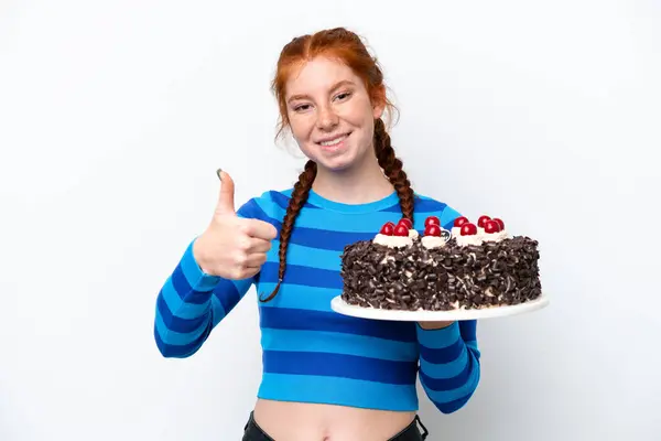 Młoda Ruda Kobieta Trzyma Tort Urodzinowy Białym Tle Kciukami Górze — Zdjęcie stockowe