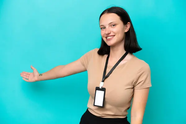 Young caucasian woman with ID card isolated on blue background extending hands to the side for inviting to come