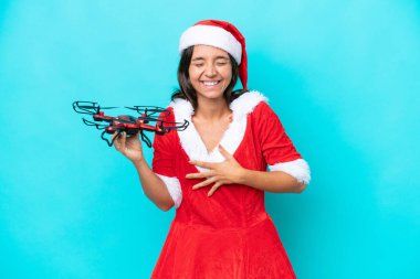 Anne Noel gibi giyinmiş genç bir kadın. Elinde mavi arka planda izole edilmiş bir dron tutuyor. Gülümsüyor.
