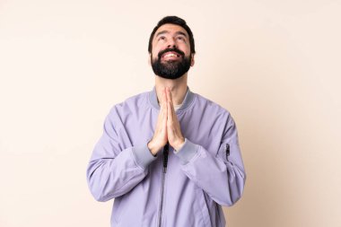 İzole edilmiş arka plan üzerine ceket giyen beyaz sakallı bir adam avuç içlerini bir arada tutuyor. İnsan bir şey ister.