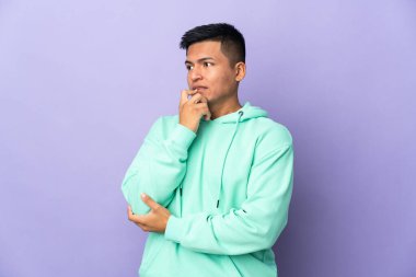 Genç Ekvadorlu adam mor arka planda izole edilmiş gergin ve korkmuş.
