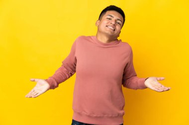 Genç Ekvadorlu adam sarı arka planda izole edilmiş mutlu ve gülümsüyor.