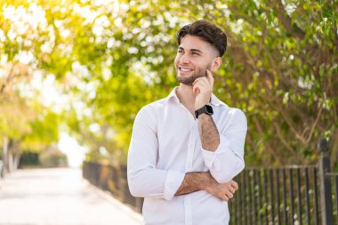 Dışarıdaki yakışıklı genç adam yukarı bakarken bir fikir düşünüyor.