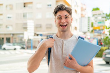 Yüzünde sürpriz bir ifade olan genç ve yakışıklı bir öğrenci.