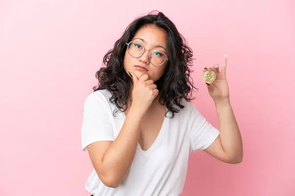 Young Asian Woman Holding Bitcoin Isolated Pink Background Having Doubts — Stock Photo, Image