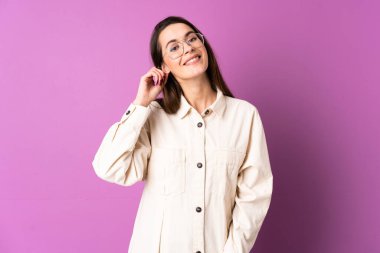 Mor arka planda yaşayan genç bir kadın gülüyor.