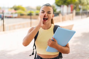 Açık havada ağzı açık bağıran genç ve güzel bir bayan öğrenci.