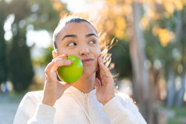 Elma tutan genç ve güzel bir bayan.