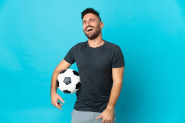 Futbolcu mavi arka planda tek başına gülüyor.