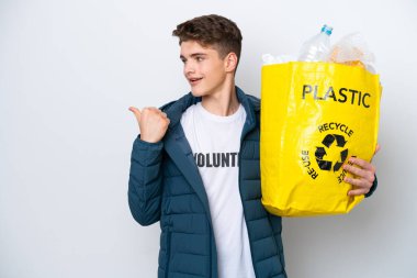 Beyaz arka planda geri dönüşüm yapmak için elinde plastik şişelerle dolu bir çanta tutan genç Rus bir ürünü sunmak için kenarı işaret ediyor.