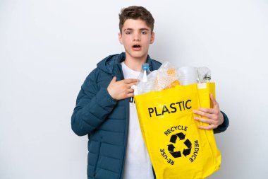 Beyaz arka planda geri dönüşüm yapmak için elinde plastik şişelerle dolu bir çanta tutan genç Rus şaşırmış ve şok olmuştu.
