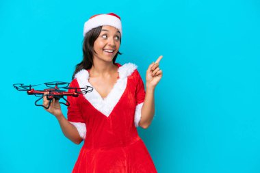 Anne Noel gibi giyinmiş genç bir kadın mavi arka planda izole edilmiş bir dron tutuyor. Çözümü bulmak için parmağını kaldırıyor.