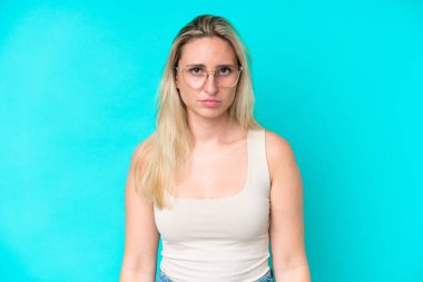 Mavi arka planda izole edilmiş, gözlüklü, beyaz bir kadın.