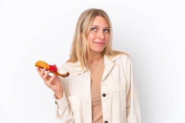 Beyaz arka planda saşimi tutan beyaz bir kadın var.