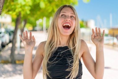 Açık havada gülümseyen genç sarışın kadın.