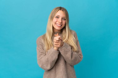 Genç sarışın kadın mavi arka planda yalnız gülüyor.