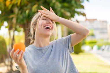 Açık havada portakal tutan genç sarışın bir kadın bir şeyin farkına vardı ve çözüme niyetlendi.